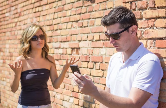 Angry man looking phone and woman up her hands