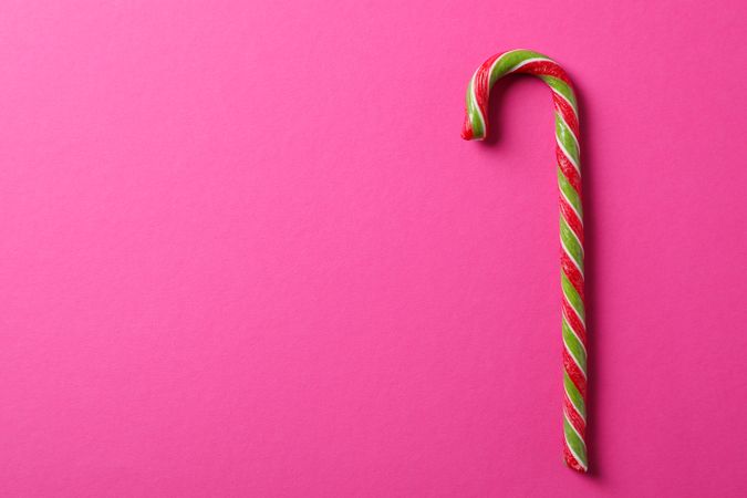 Sweet candy cane on pink background, space for text