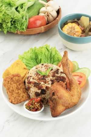 Indonesian chicken dish served with rice, salad and spicy condiment with soup