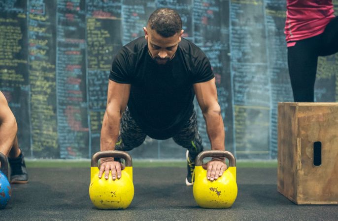 Sportsman doing push-ups with kettlebells
