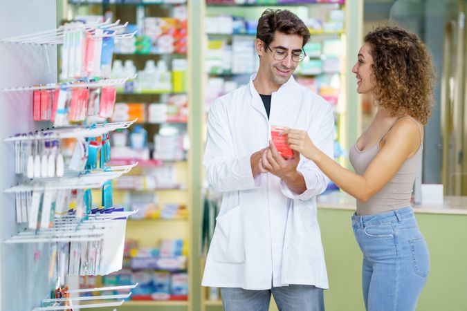 Happy man pharmacist explaining drug details to woman customer