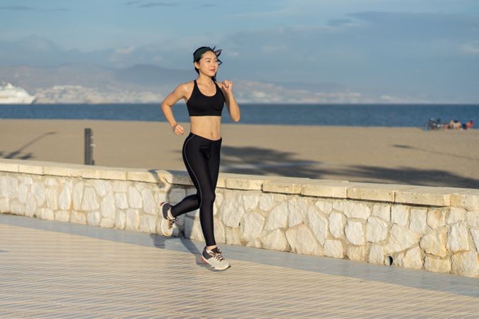 Sportswoman running on beach on sunny day