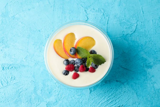 Bowl with sour cream yogurt and fruits on color background