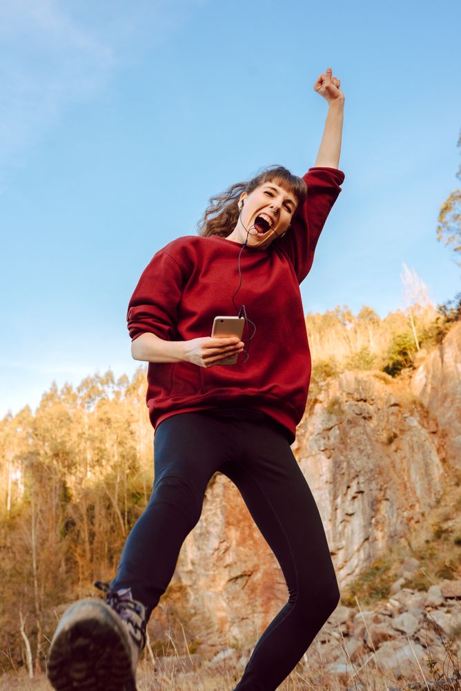 Young woman with smartphone dancing