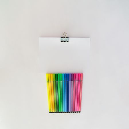 Row of colorful pens with notepaper and copy space