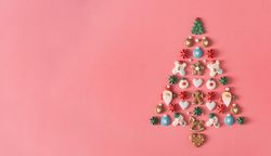 Festive tree made out of holiday cookies on salmon background