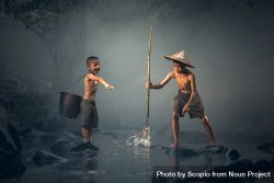 Two Asian boys fishing in shallow water in the river 5RzjJ5