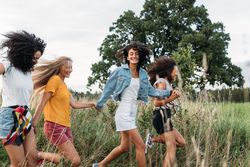 Female friends having fun in long grass outside