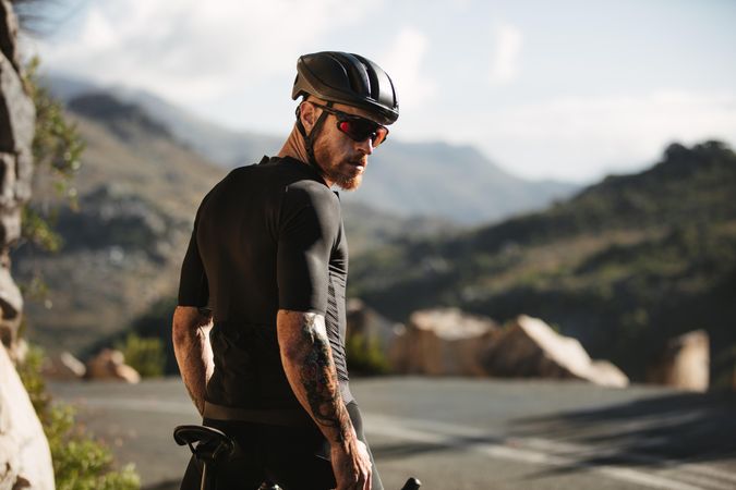 Tough male athlete riding bicycle and practicing outdoors on mountain road