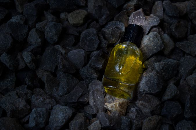 Yellow perfume bottle mock up laying in the rocks