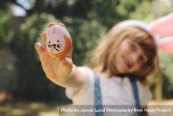 Smiling girl holding a painted easter egg in her hand be7YK5