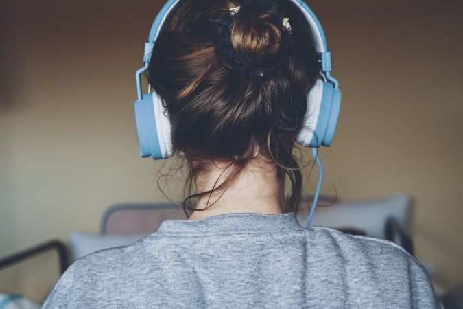Back view of young woman wearing headphone indoor