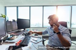 Young entrepreneur dialing a call using telephone at office desk bG2de4