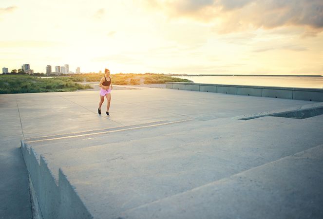 Woman running towards stairs with cityscape in background