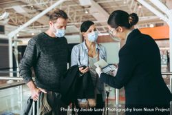 Man and woman with airlines staff at boarding gate of airport during pandemic bYRoD0