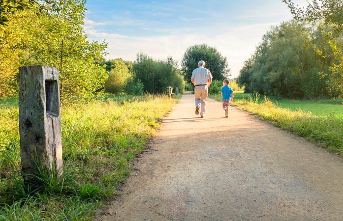 Back of older man and happy child running outdoors