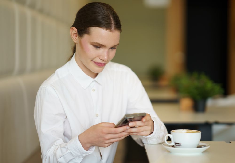 Businesswoman using phone in a chic cafeteria