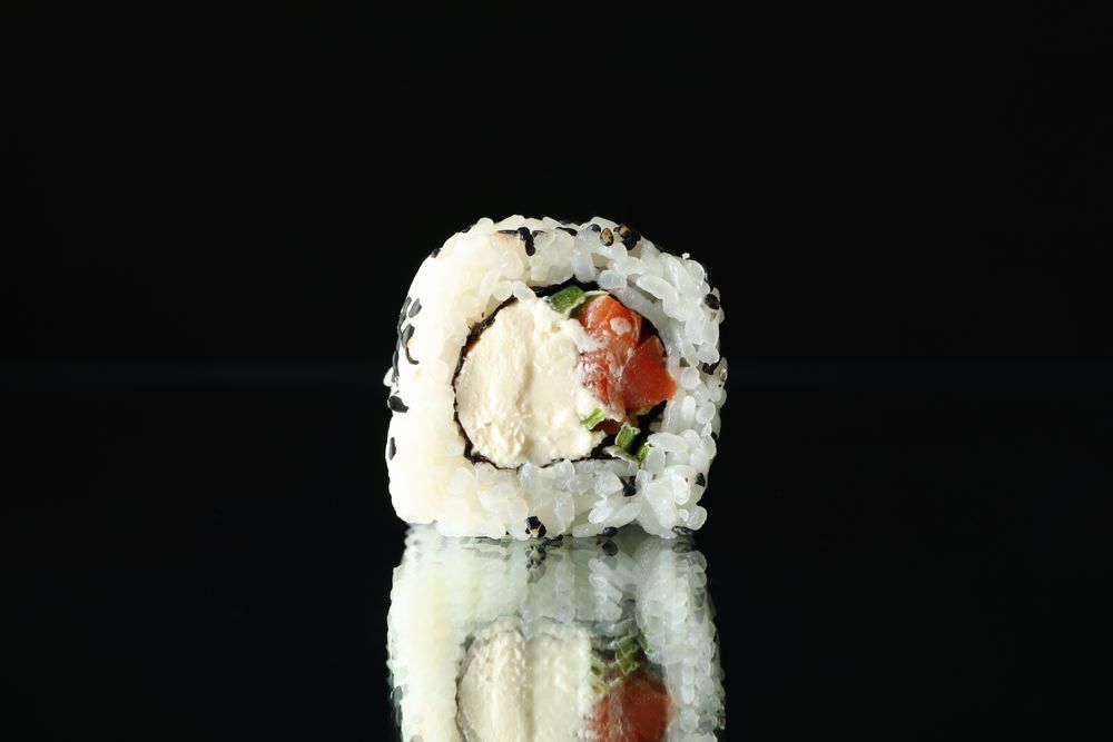 Sushi roll on dark mirror background, close up