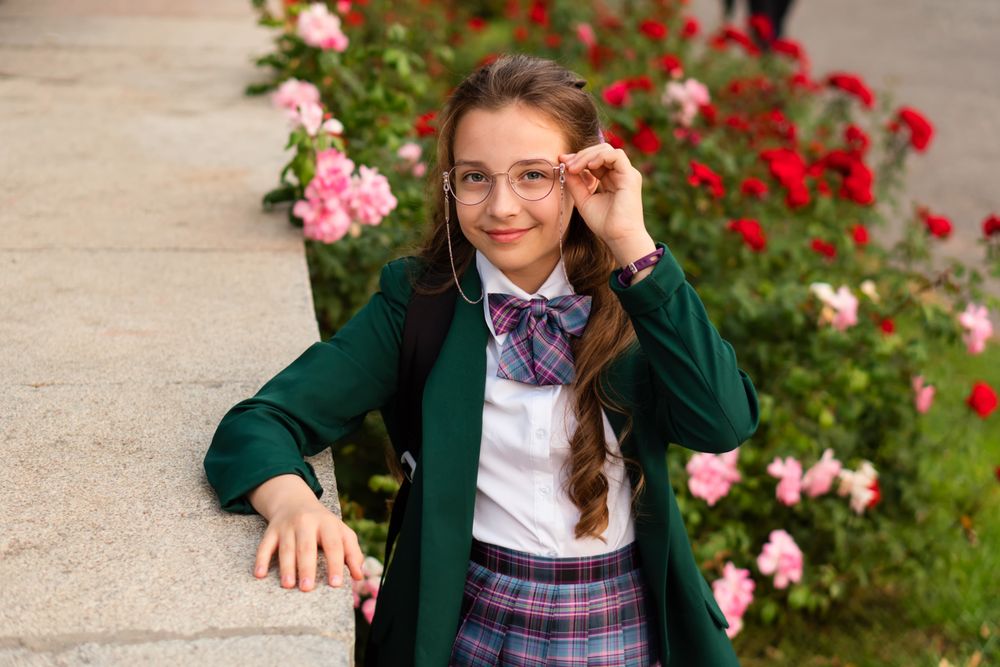 Young girl in school uniform adjusting her glasses