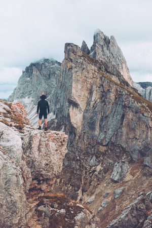 Back view of man standing on rock formation mountain in Dolomites, Italy