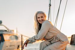 Happy older woman with long hair leaning on sailboat railings
