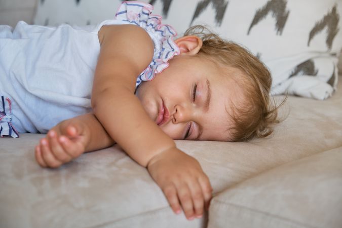 Adorable toddler napping on sofa