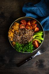 Healthy dinner with buckwheat, lettuce, avocado, and meat on wooden table