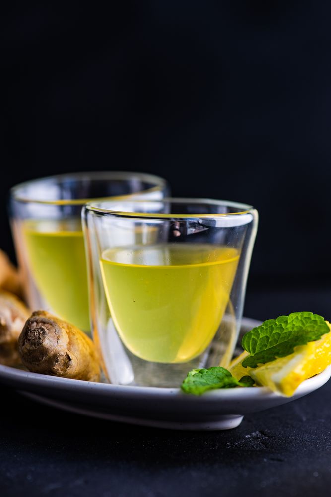Close up of two yellow detox drinks with ginger and lemon