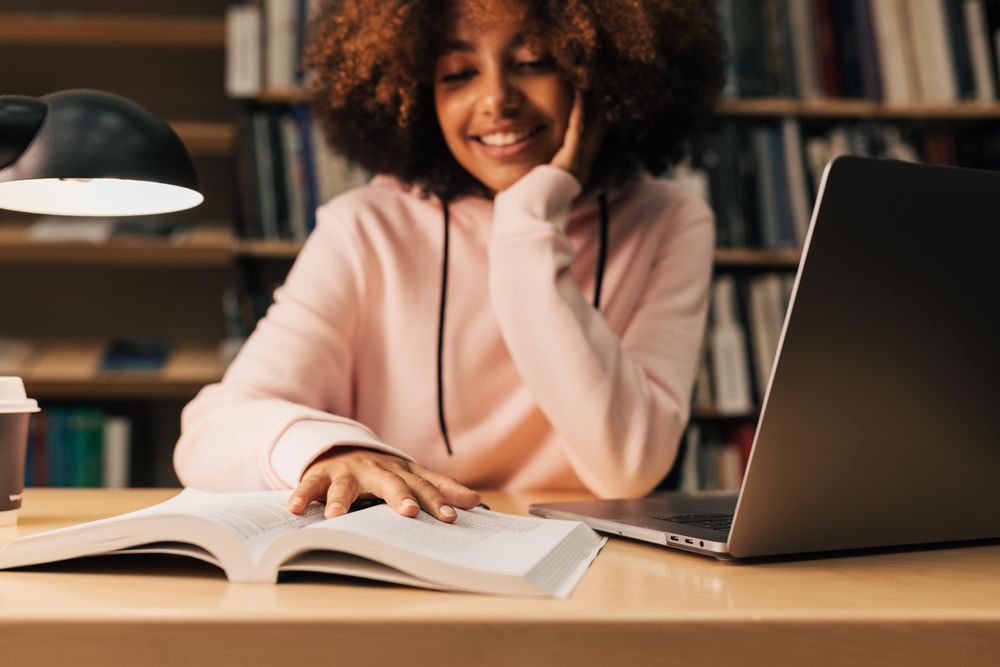 Teenage female student doing homework in library