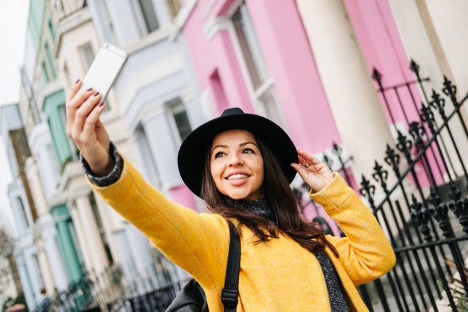 Stylish woman using smartphone near house on street