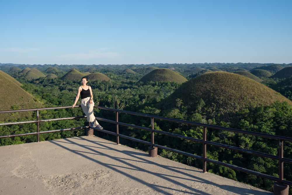 Happy woman standing on observation deck on hill