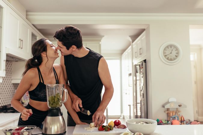 Fit young couple in love preparing healthy smoothie in kitchen