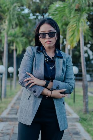 Confident businesswoman posing in a park with palm tree backgrou
