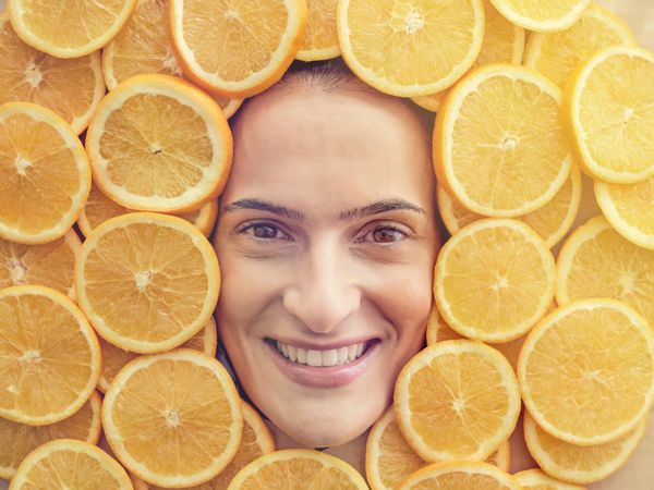 Smiling woman among slices of ripe oranges
