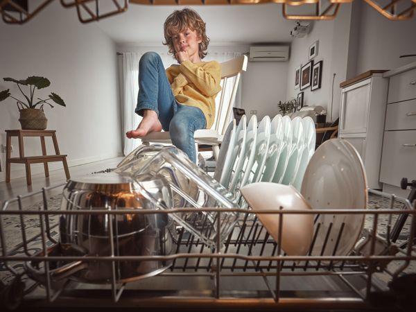 Boy sitting near modern dishwasher