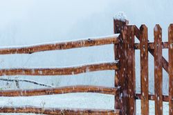 Wooden fence between snowfall in winter