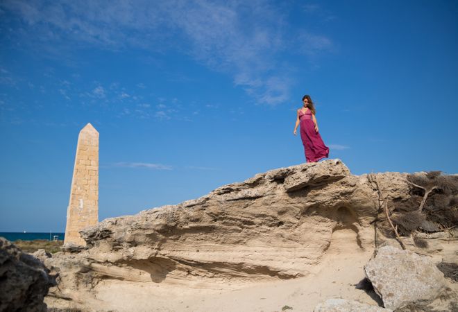 Woman in dress standing near stone monument