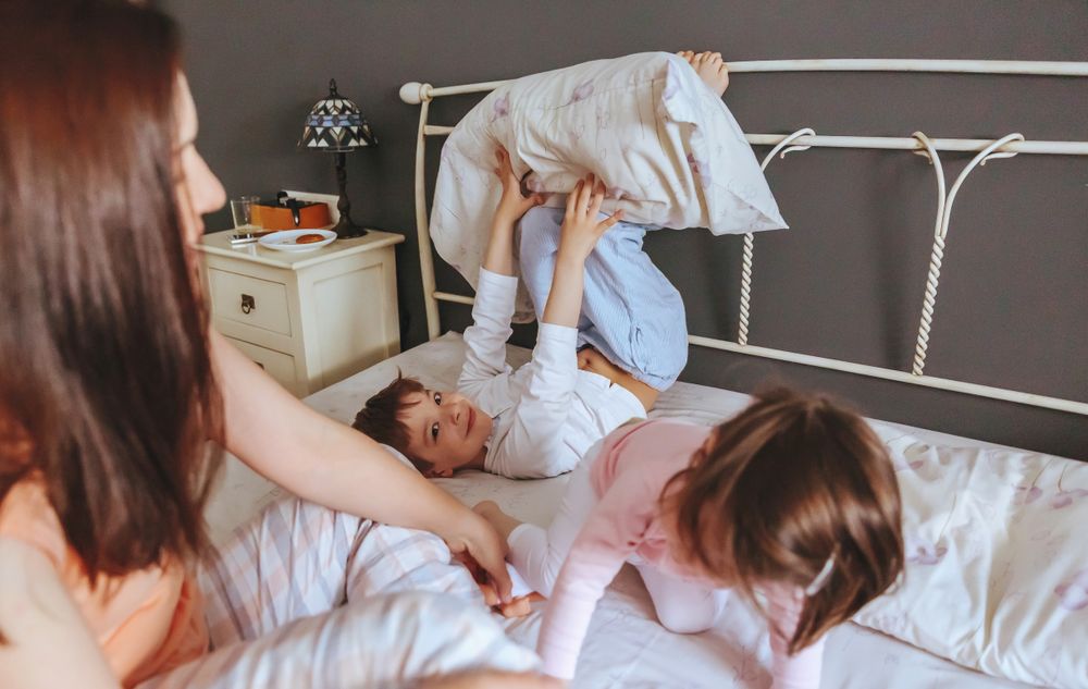 Little boy and girl playing in bed on a relaxed morning with their mother