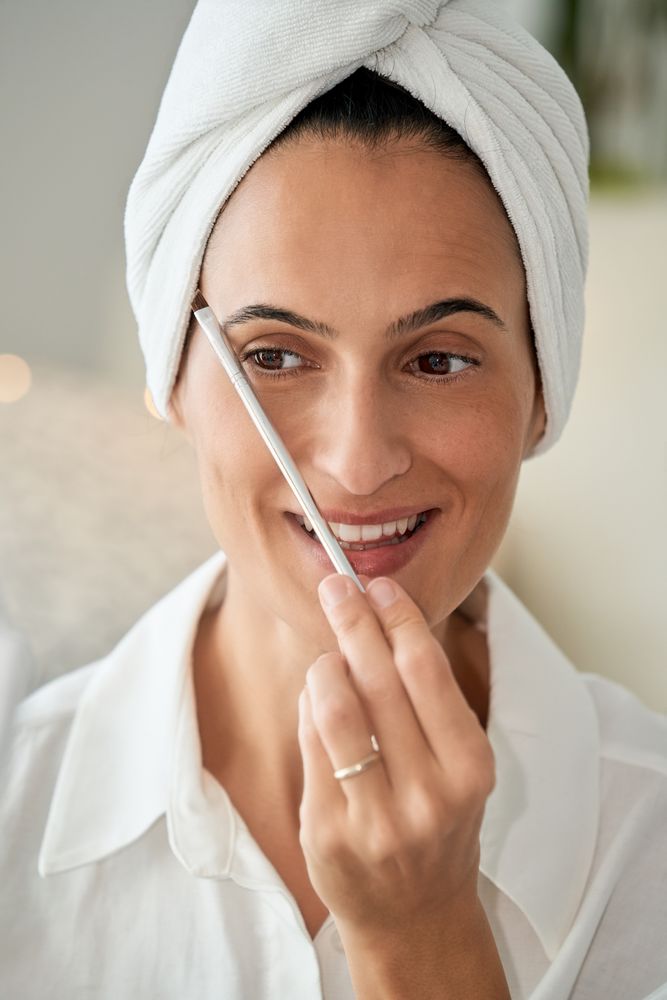 Smiling woman applying eyebrow shadow