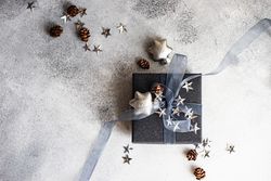 Top view of festive Christmas card concept with blue gift box on grey background with space for text