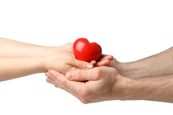 Female and male hands hold heart, isolated on blank background