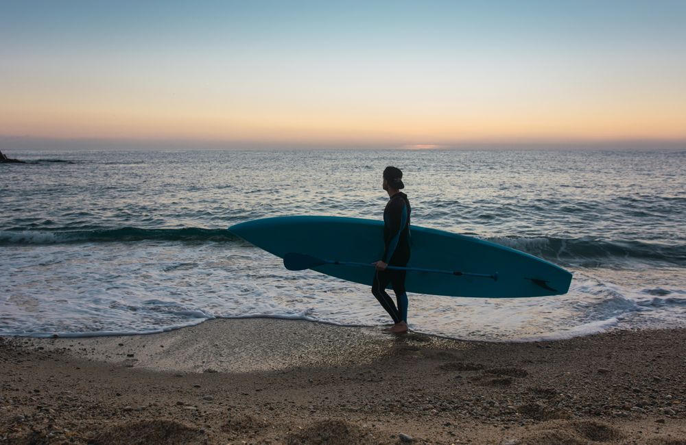 Man practicing paddle surfing with neoprene in a sunrise