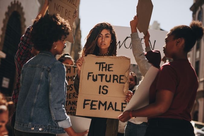 Women protesters hold up signs of the future is female