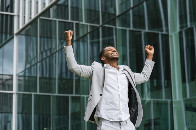 Enthusiastic Black man rejoicing raising hands up