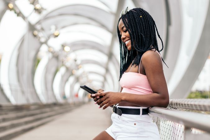 Portrait of a Black young woman enjoying the summer in the city using smartphone