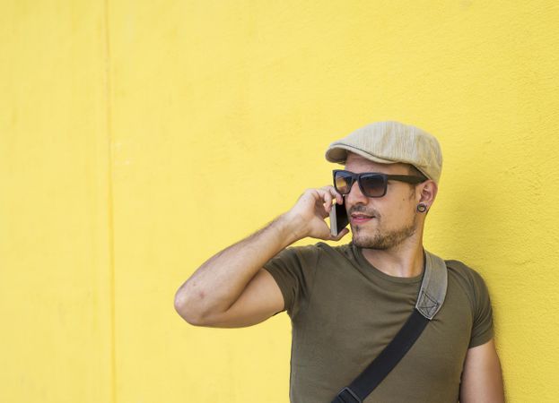 Male in hat and sunglasses taking call on phone, copy space