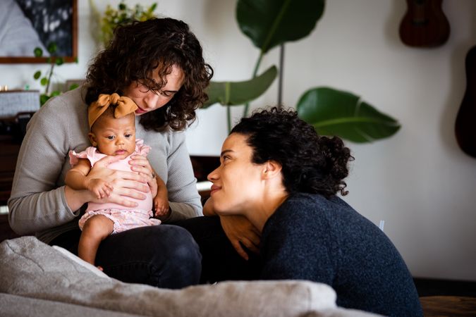 Happy married couple relaxing with baby in living room