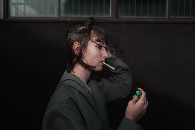 Female teenager in casual clothing smoking cigarette at city street