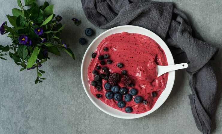 Smoothy of fresh bog blueberries and raspberries in bowl near napkin