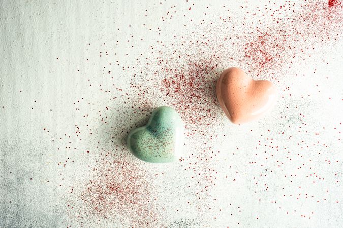 Two ceramic hearts on table with glitter